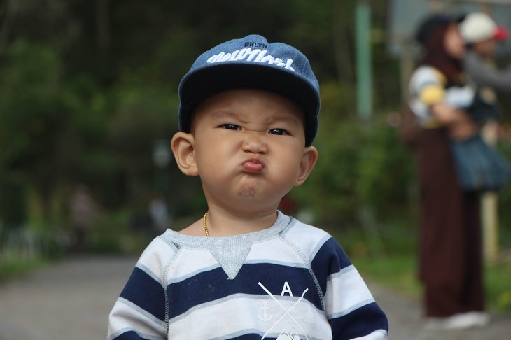a boy is wearing a baseball cap and making a funny face