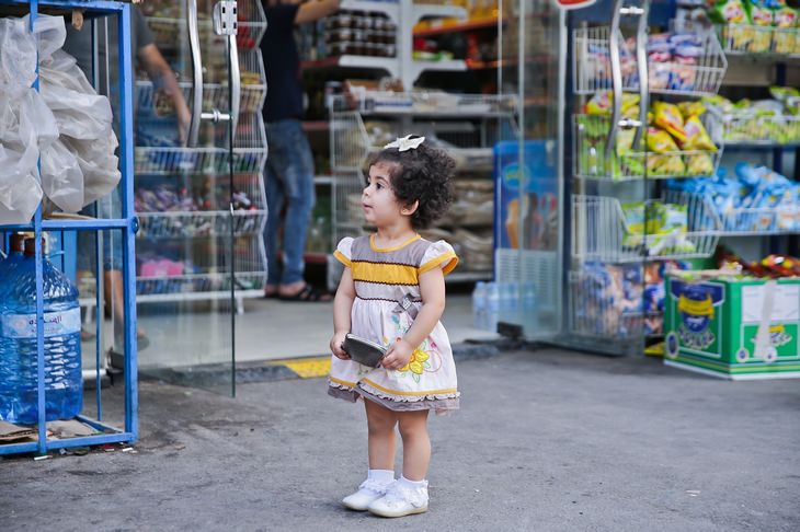 a girl is standing near a shop and holding a wallet