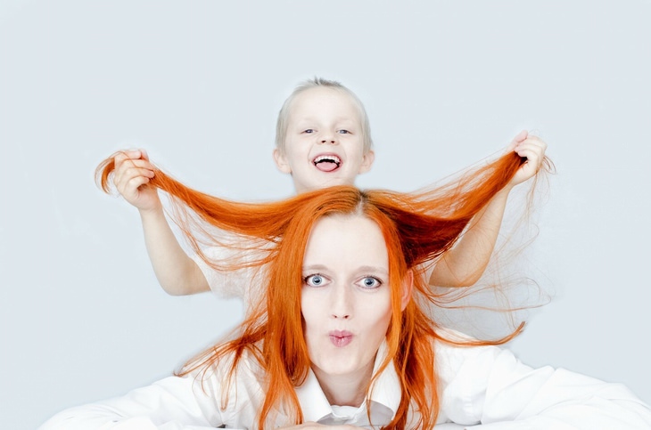 a boy is holding a woman's hair up and they are making funny faces