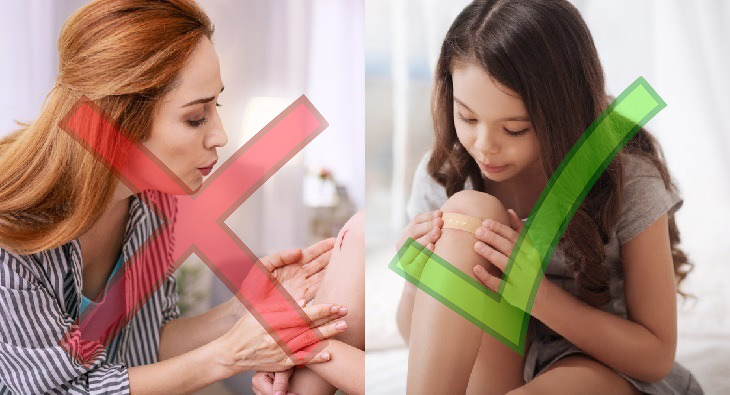 woman blowing on a scratch and girl covering a wound with a bandaid