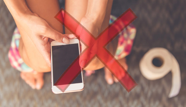 woman sitting on the toilet with a smartphone