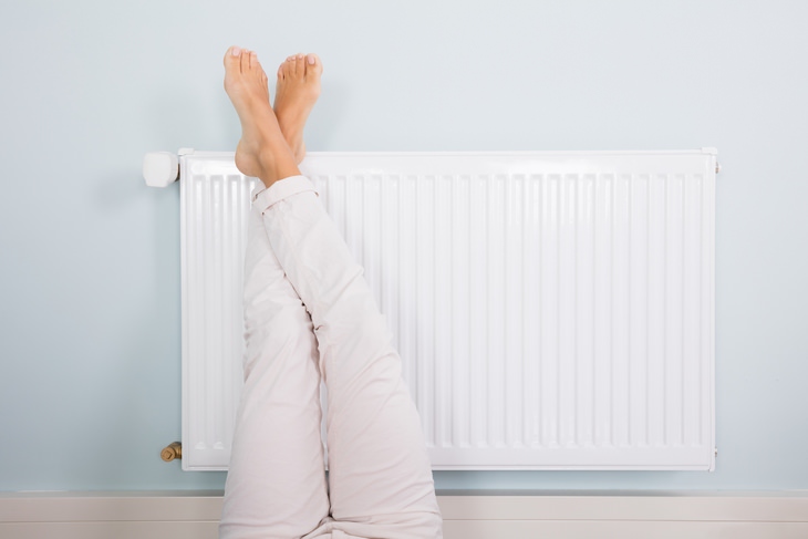 a woman resting her feet against the radiator