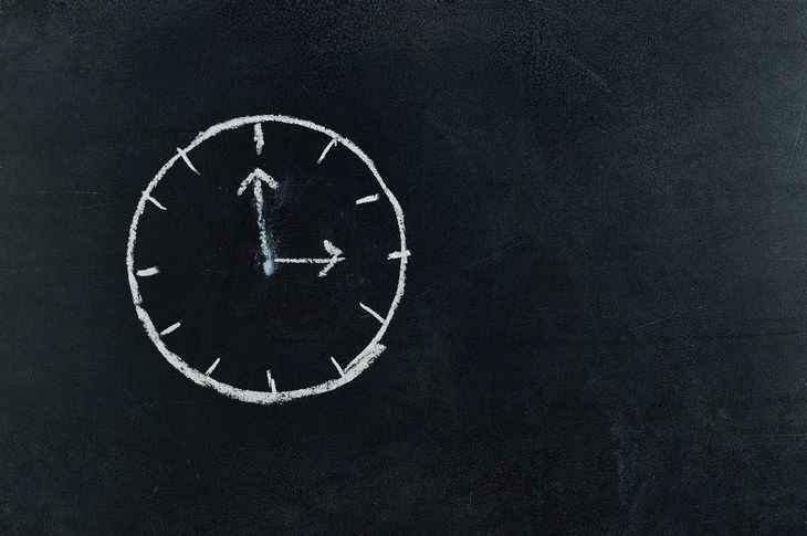 a clock drawn on a chalkboard with white chalk