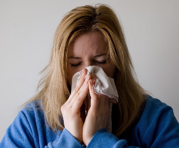 woman sneezing blowing her nose