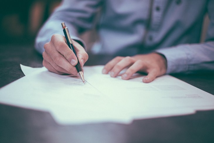 a person writing in a notebook with a pen