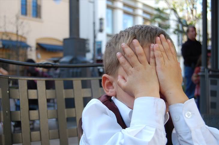 a boy covering his face with his hands