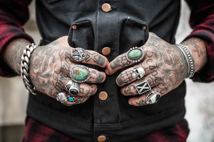 a man's tattoed hands with rings and bracelets