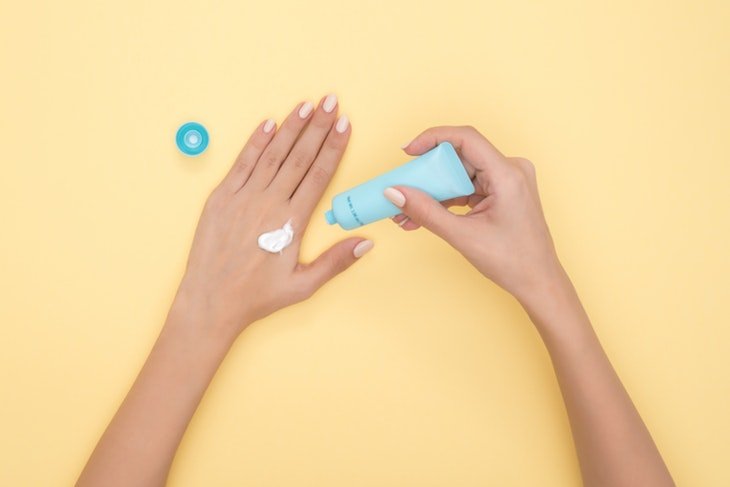 a woman applying cream to her hands