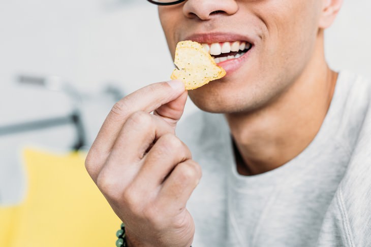 traveler's bloating causes and fixes man eating a chip