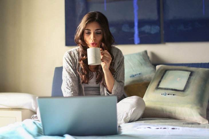 weird beneficial habits woman drinking tea using a laptop