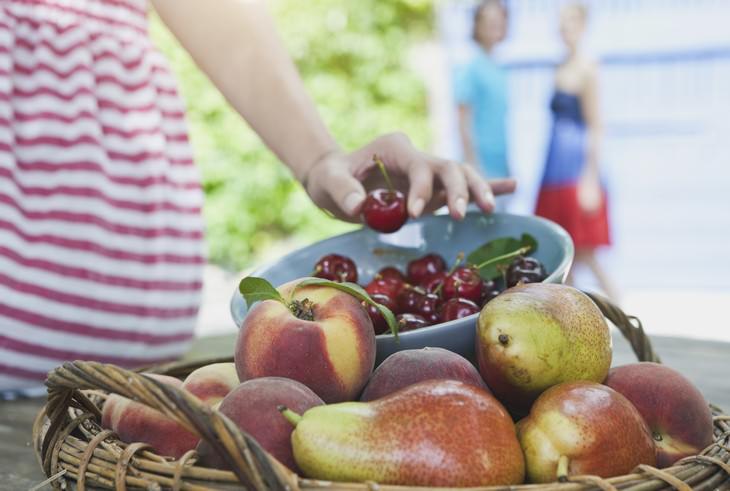 10 Foods That The World’s Longest Living People Eat a bowl of fruit and girl picking up a cherry