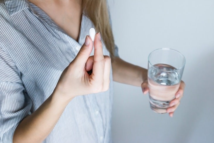Habits Bad for Eyes woman holding a glass of water taking a pill