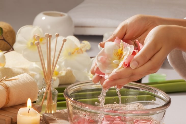 rose water woman holding rose over bowl of rose water