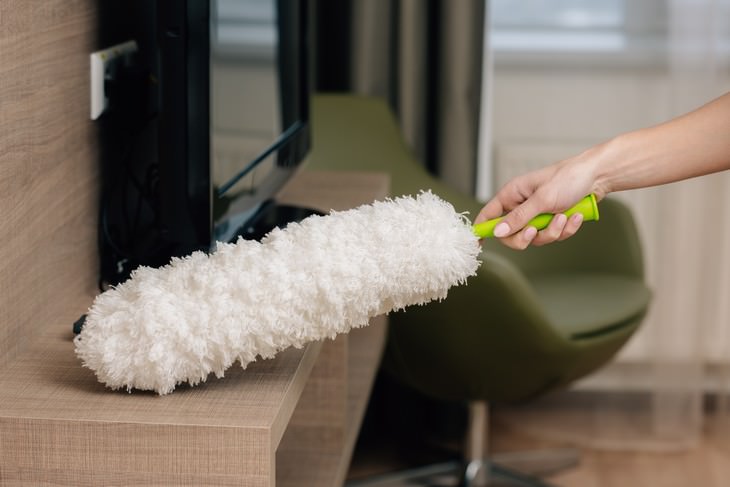 Furniture Cleaning Mistakes cleaning TV stand using a feather duster