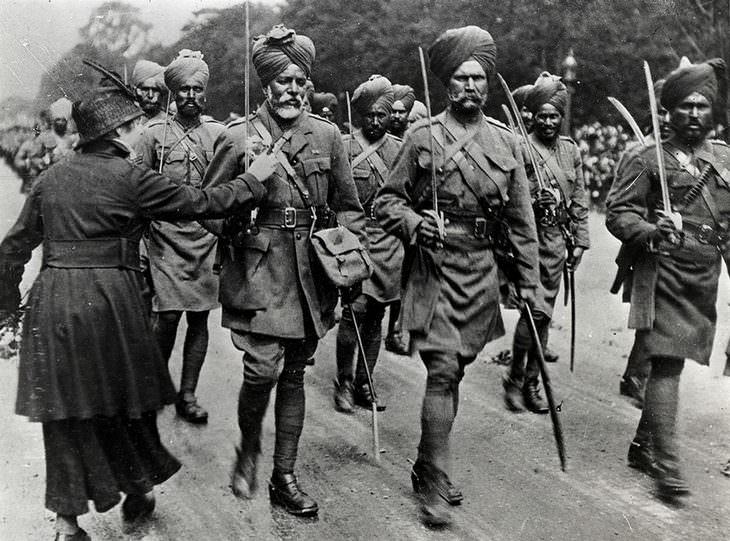 historical photos A French woman attaching flowers to uniforms of British-Indian army soldiers who assisted the fighting in France 