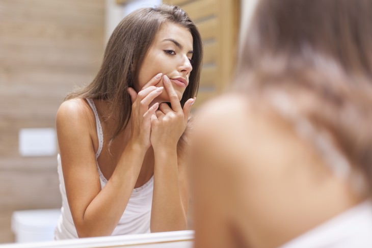 Health Benefits of  Manuka Honey woman touching her skin in front of the mirror
