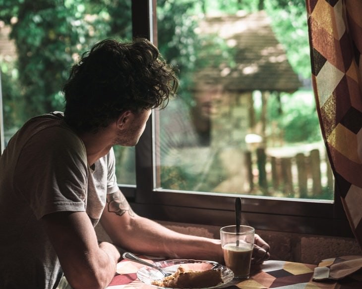 tips to get out of bed man looking out of window while having breakfast