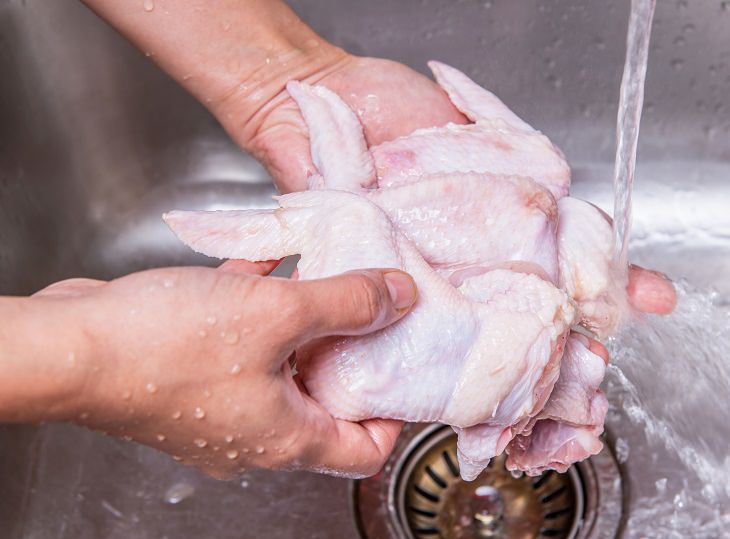 washing raw chicken wings in a sink