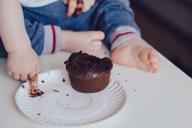 dark chocolate child eating a chocolate cupcake