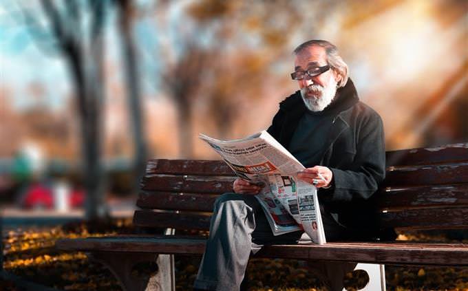personality quiz: senior man reading newspaper on a bench