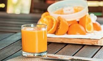 glass of orange juice next to sliced oranges