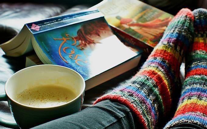 woman's legs next to book and soup bowl