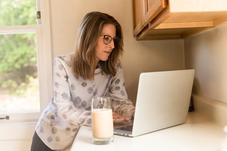 foods safe to eat past expiration date woman looking at a laptop with a glass of milk