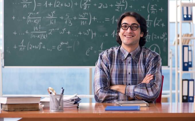 Math quiz: math teacher in front of blackboard with equations happy