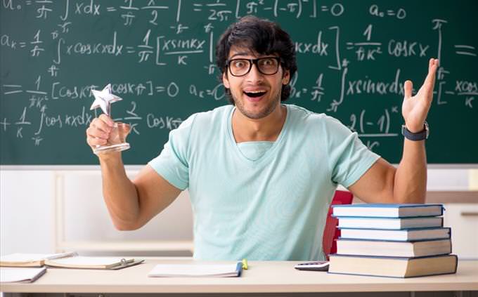 Math quiz: math teacher in front of blackboard with equations excited holding a star