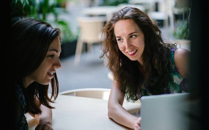 two women sitting in front of a laptop