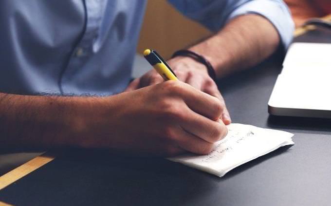 man writing with a pen on paper