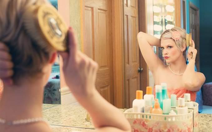 a woman combing her hair in front of a mirror