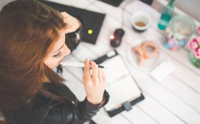 a woman thinking in front of a notebook