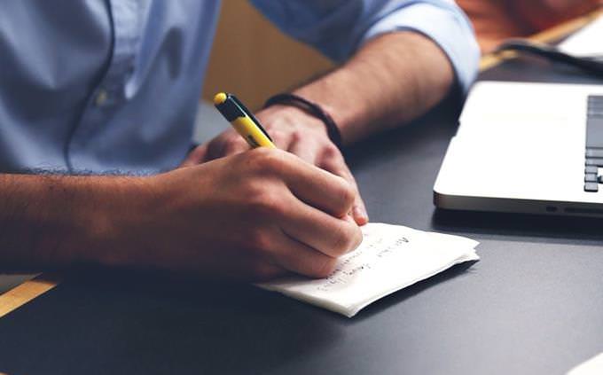 man writing on top on table