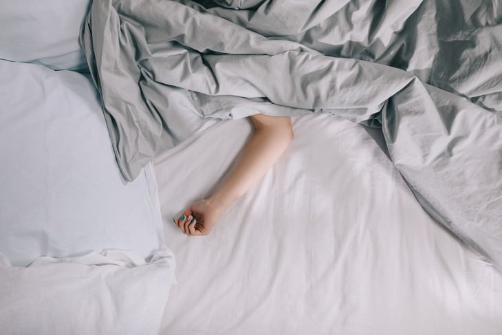 Study Finds Weighted Blankets Can Cure Insomnia hand peeks from under a blanket