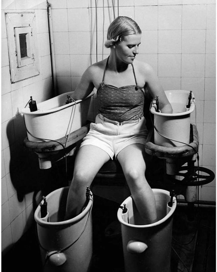 Past Beauty Practices That Seem Strange Today, young woman holds her arms and legs in four water bathes with electric current, to improve blood circulation, c. 1938