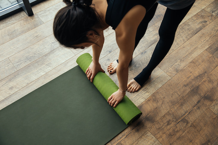 Restorative Yoga: Health Benefits and Simple Poses, woman rolling yoga mat