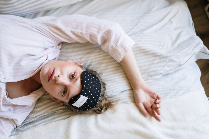 Dark Circles Causes and Tips woman in bed with an eye mask