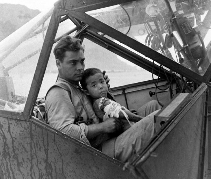 Historical Photos An American soldier cradles a wounded Japanese boy and shelters him from the rain in the cockpit of an airplane during the Battle of Saipan while waiting to transport the youngster to a field hospital.