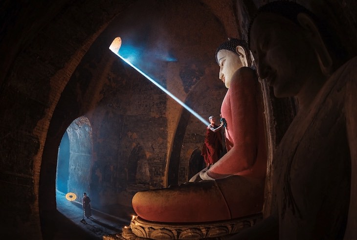 12 Unforgettable Photos of Asia by Zay Yar Lin, Novices at work while the sunray falls upon the Buddha statu