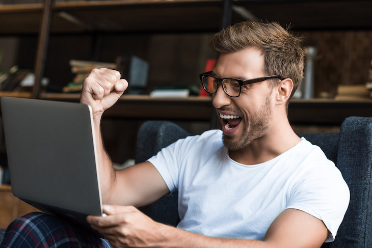 How to Beat Self Doubt & Get Closer to Your Goals, man cheering in front of laptops