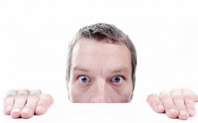 Scared man peeking from under a table