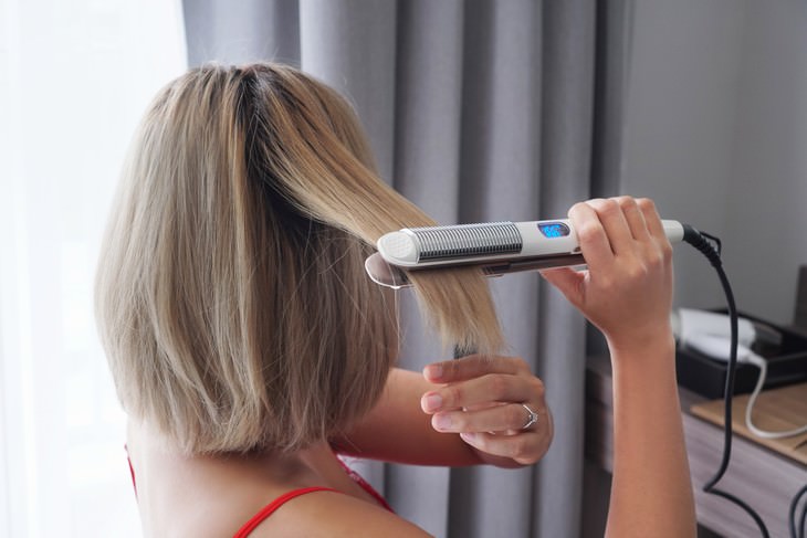 Tips to Help You Get Rid of Greasy Hair woman straightening her hair