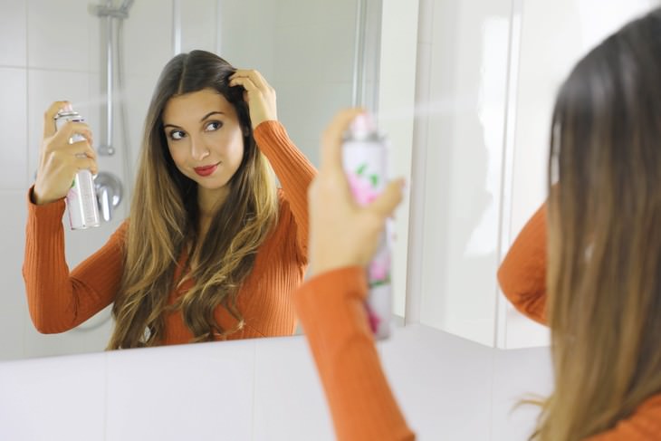 Tips to Help You Get Rid of Greasy Hair woman applying dry shampoo