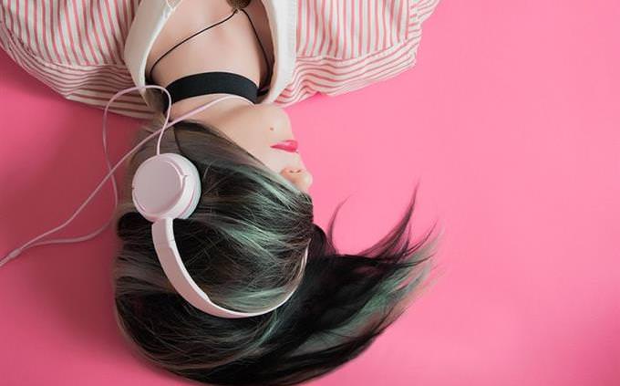 woman lying down and listening to headphones