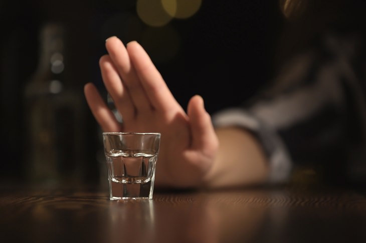 dangers of energy drinks hand pushing away a glass with alcohol