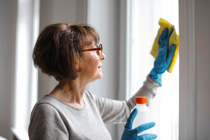 Spring Cleaning Health Benefits woman cleaning windowsill