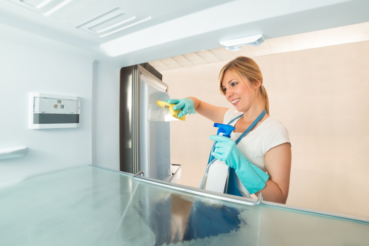 Spring Cleaning Health Benefits woman cleaning fridge