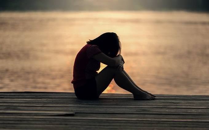 a sad woman sitting on the beach