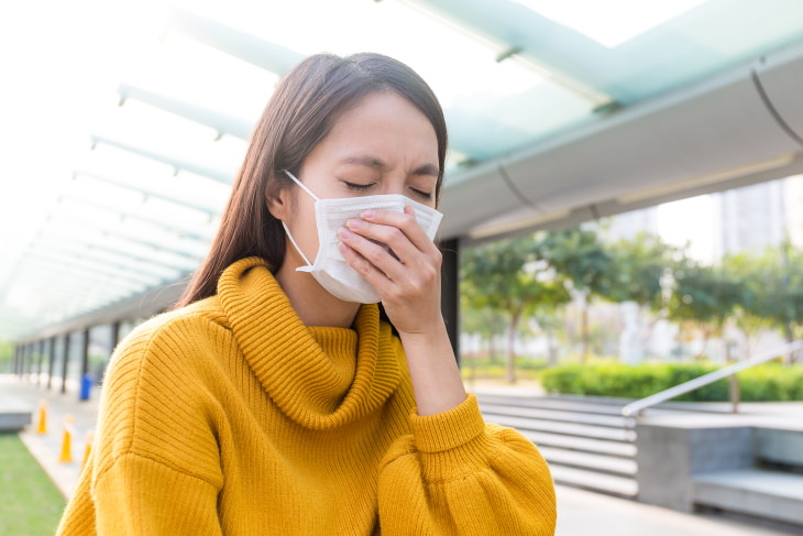 allergies vs coronavirus woman in mask sneezing